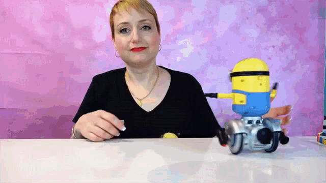 a woman is sitting at a table with a toy minion on it