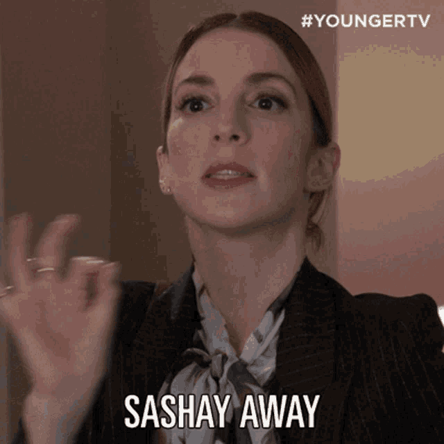 a woman in a suit says sashay away with her hands up