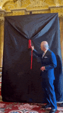 a man in a suit is opening a black curtain
