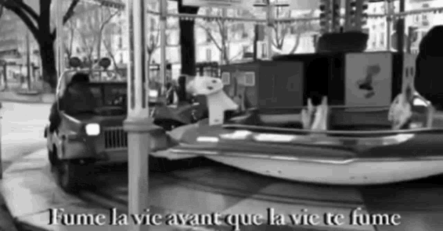 a black and white photo of a merry go round with the words fume la vie avant que la vie te fume below it