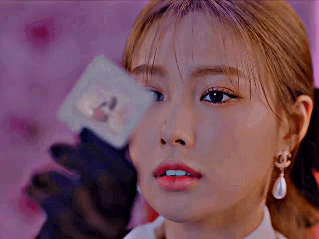 a close up of a woman 's face with a card in her hand that says a on it