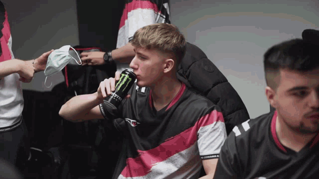 a man drinking a monster energy drink in a locker room