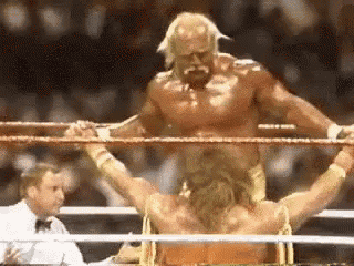 a wrestler is standing in a boxing ring with his arms outstretched .