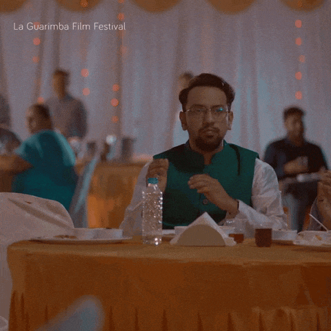 a man sitting at a table with a bottle of water in front of him and the words la guarimba film festival below him