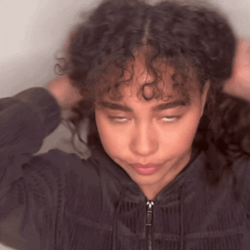 a woman with curly hair has her eyes closed