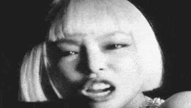 a black and white photo of a woman with short blonde hair making a funny face .