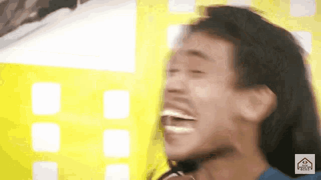 a man with a beard is laughing with his mouth open and his eyes closed .