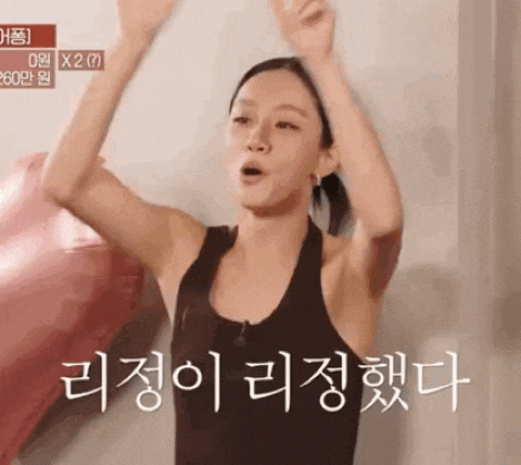 a woman in a black tank top is raising her arms in the air in a foreign language .