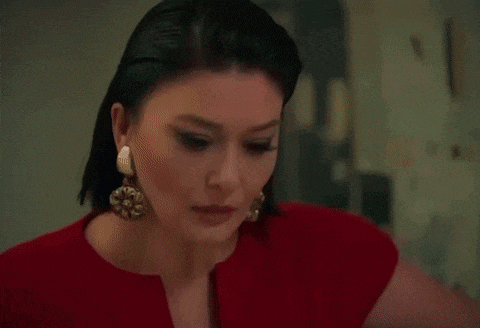 a woman in a red dress is walking down a hallway holding a pair of shoes .