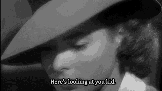 a woman in a hat says here 's looking at you kid .