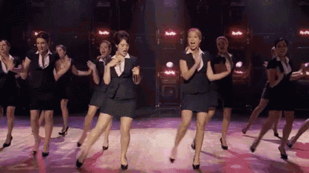 a group of women are dancing on a stage in a row .
