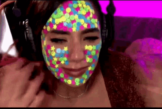a woman is wearing headphones and has a colorful face painted on it .