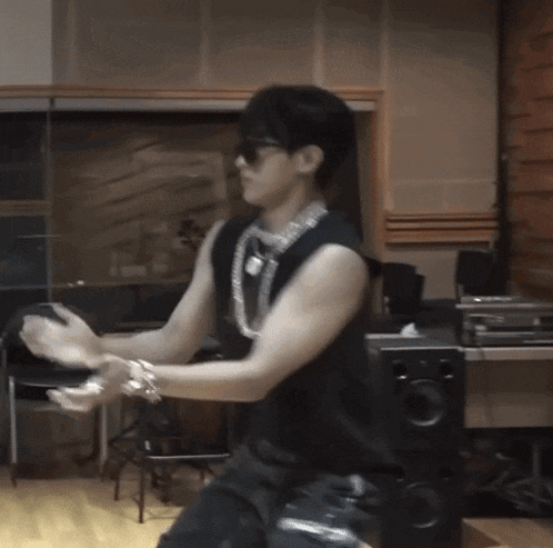 a man in a black tank top is dancing in front of a speaker