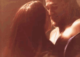 a man and a woman are kissing each other in a room .