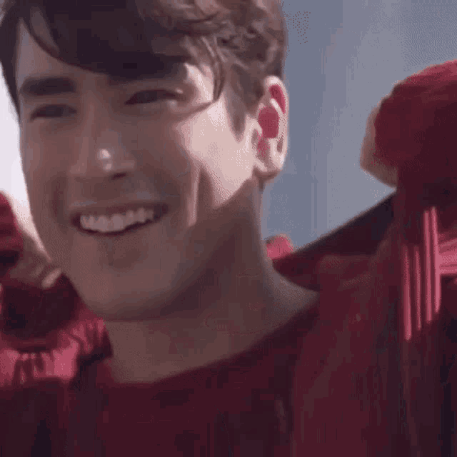 a close up of a man wearing a red hoodie smiling .