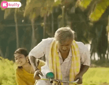 an elderly man is riding a bicycle with a young woman sitting on his back .