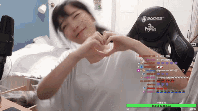 a girl is making a heart shape with her hands in front of a sades gaming chair