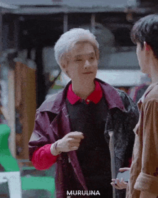 a man with gray hair is talking to another man .