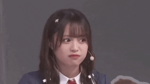 a young woman wearing a microphone and headphones is making a face .