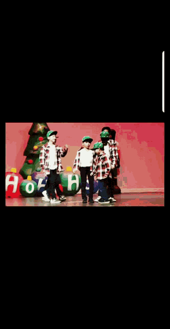 a group of young boys are dancing on a stage in front of a christmas tree