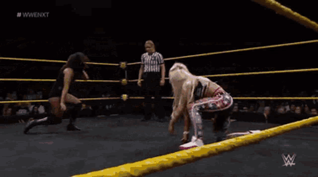 a wrestler is upside down in a wrestling ring while a referee looks on