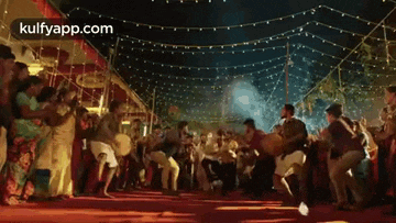 a group of people are dancing and playing drums in a room with lights .