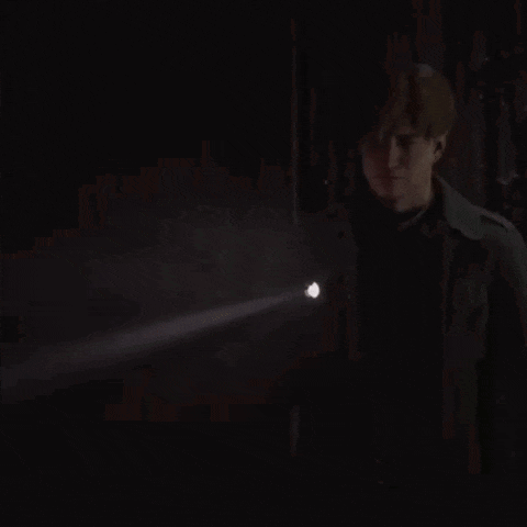 a man in a dark room is holding a flashlight .