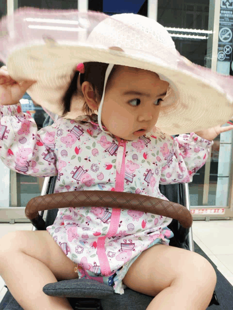 a little girl wearing a stroller with a hat on her head