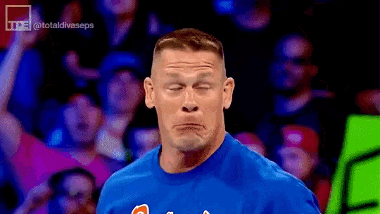 a man in a blue shirt making a face in front of a crowd