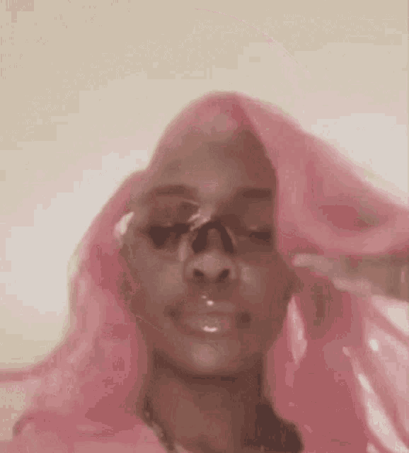 a woman with pink hair is wearing sunglasses and a nose ring .