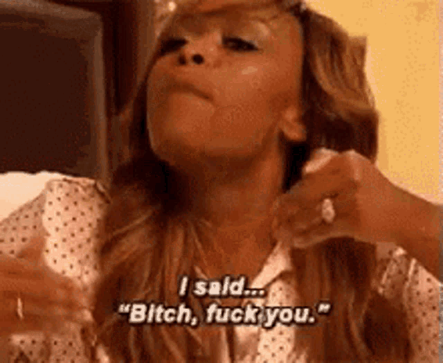 a woman is sitting on a bed and saying `` bitch , fuck you '' .