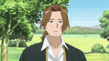 a man with brown hair and a ponytail stands in a field with trees in the background
