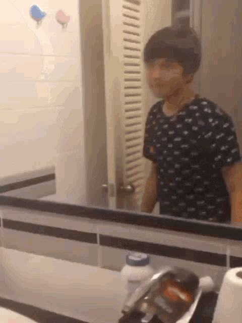 a man standing in front of a bathroom mirror with a bottle of lotion on the counter