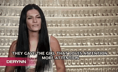 a woman is standing in front of a wall of empty glasses and says they gave the girl that loves attention more attention