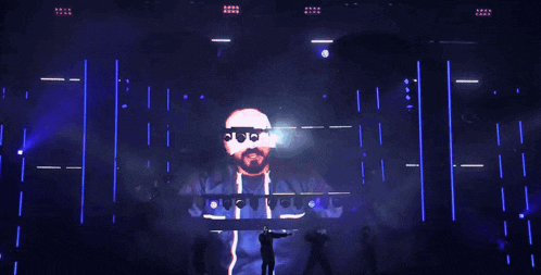 a man stands on a stage with a large screen behind him that says ' o'o'o ' on it