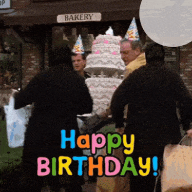 a group of people standing in front of a bakery with a birthday cake in front of them