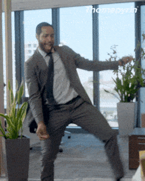 a man in a suit and tie is dancing in front of a window with the word thomapyrin behind him