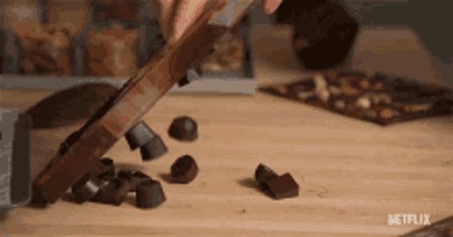 a person is cutting chocolate on a wooden table with a netflix logo in the background