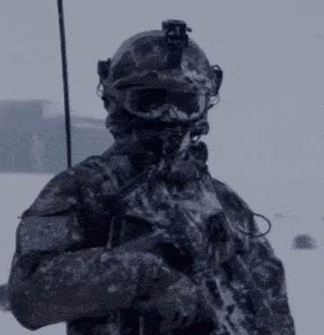 a soldier wearing a helmet and goggles is holding a gun in the snow