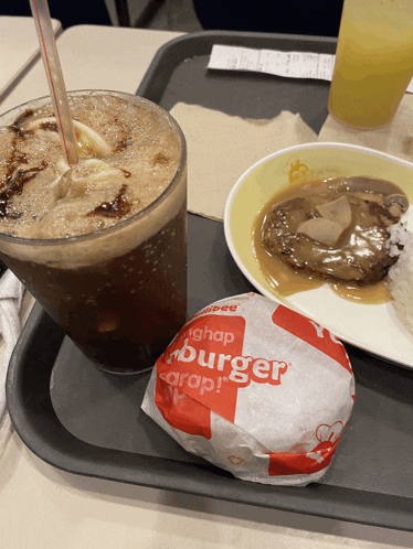 a hamburger and a drink on a tray with a wrapper that says ' hamburger ' on it