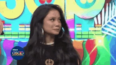 a woman is standing in front of a colorful background with the word asap on the bottom