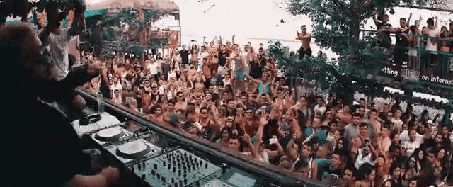 a dj is playing music in front of a crowd of people at a party .