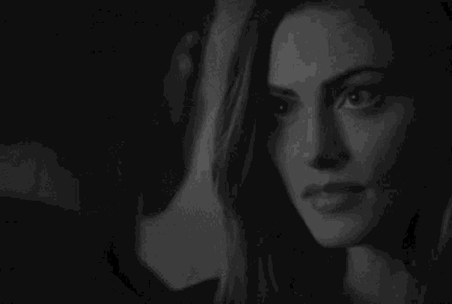 it is a black and white photo of a woman looking out a window .