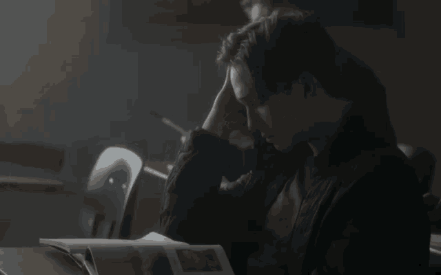 a man is sitting at a desk in a classroom with his head in his hands .