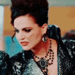 a woman wearing a necklace and earrings looks angry .