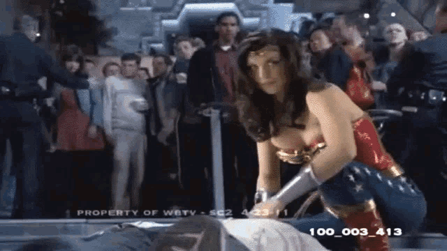 a woman in a wonder woman costume is standing next to a man laying on the ground