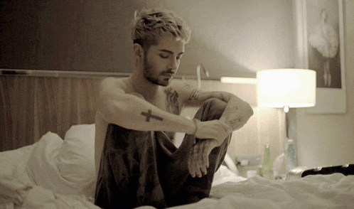 a shirtless man with a cross tattoo on his arm