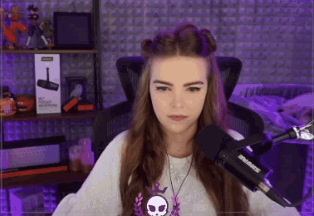 a woman sitting in front of a shure microphone