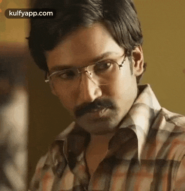 a man wearing glasses and a mustache is looking at something .