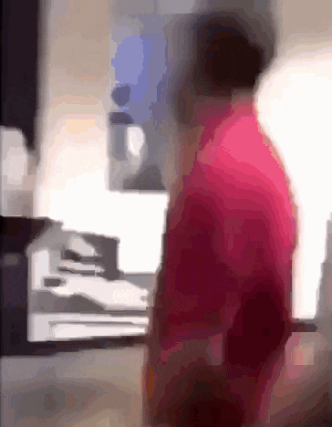 a blurry picture of a man in a pink shirt standing in front of a computer .